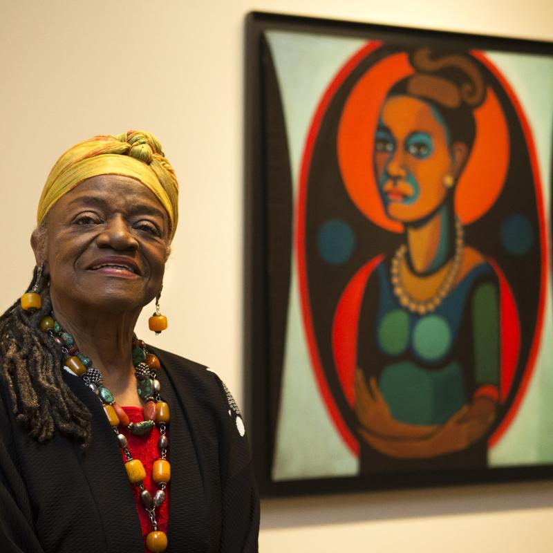 Artist Faith Ringgold in front of her painted self portrait