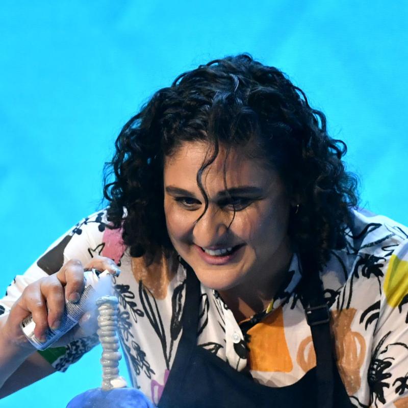 Chef Samin Nosrat sprays an aerosol onto a food creation while wearing an apron